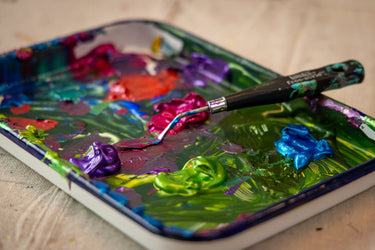 Artistic palette with colorful paint and a brush on a wooden surface